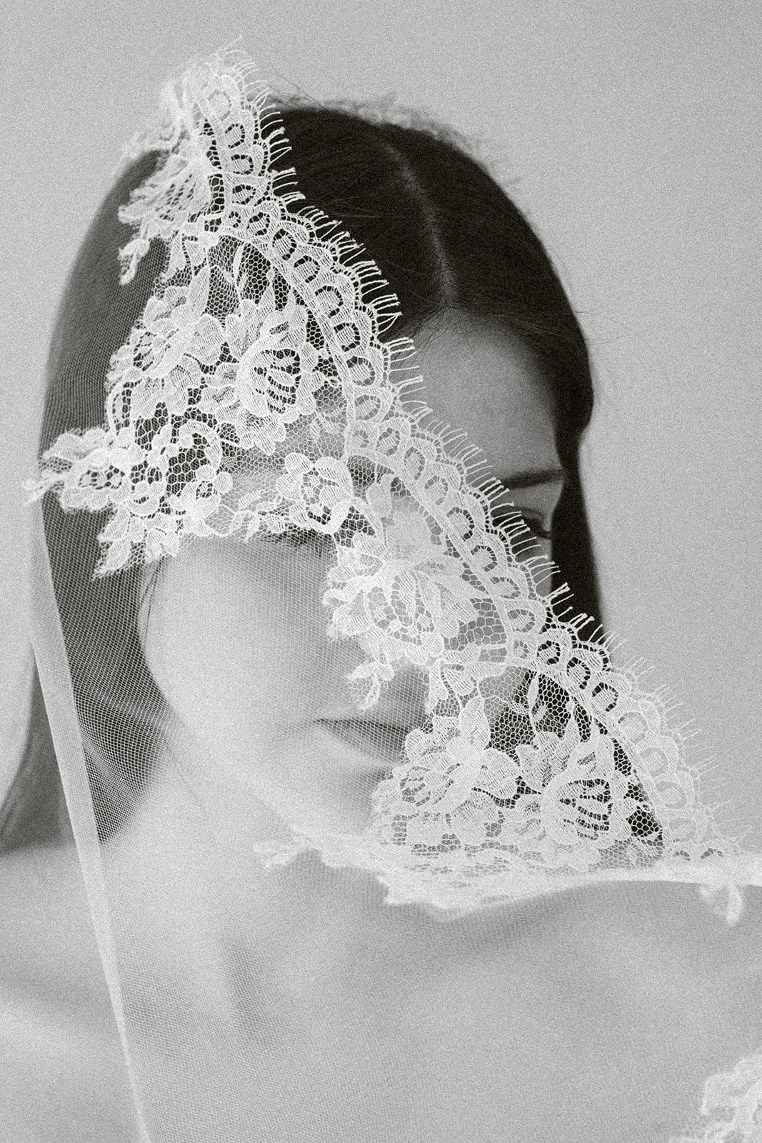French leavers lace invisible tulle veil partially covering the face of a demure bride