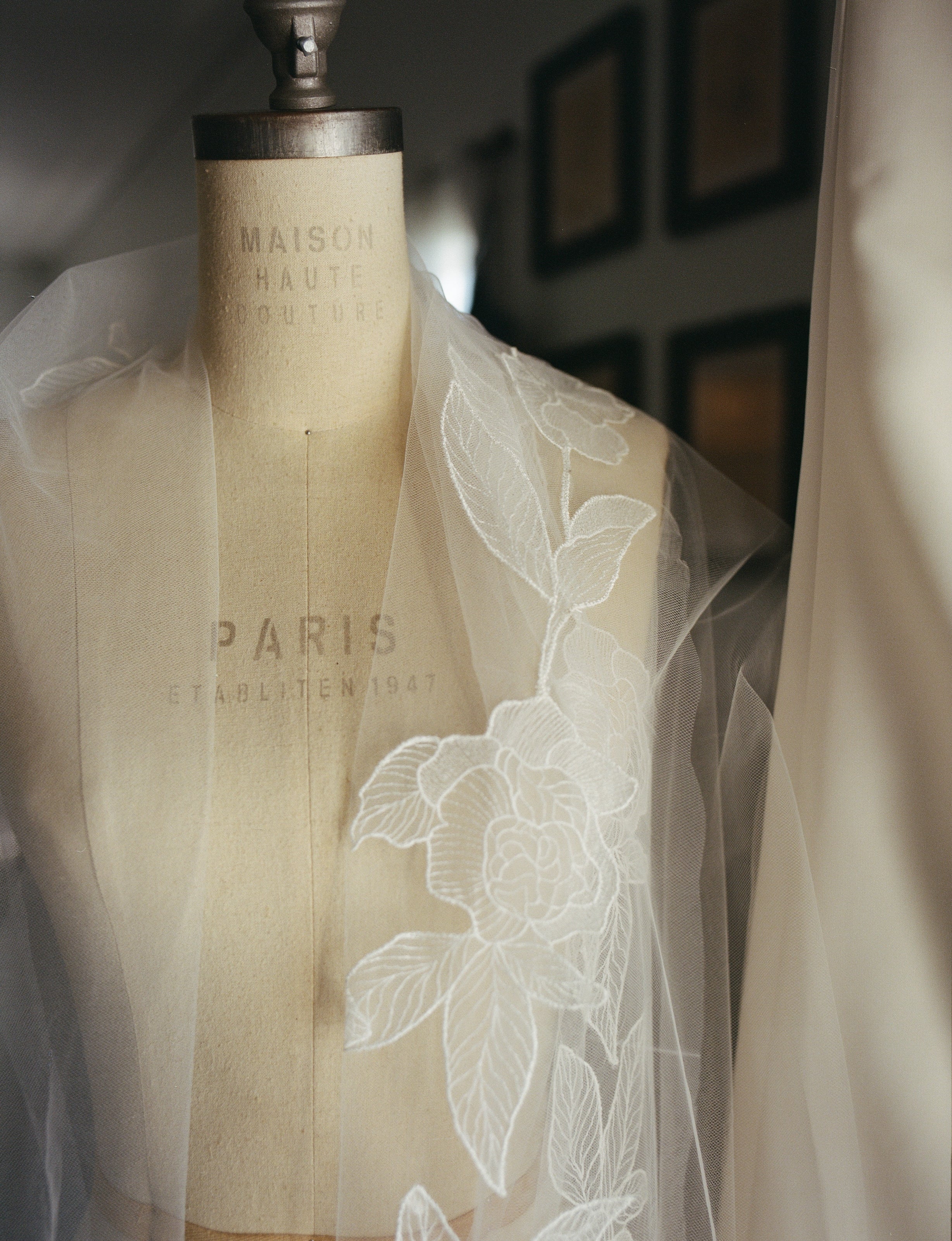 Light ivory peony botanical lace veil draped on a wooden mannequin with 'Maison Haute Couture Paris' branding.
