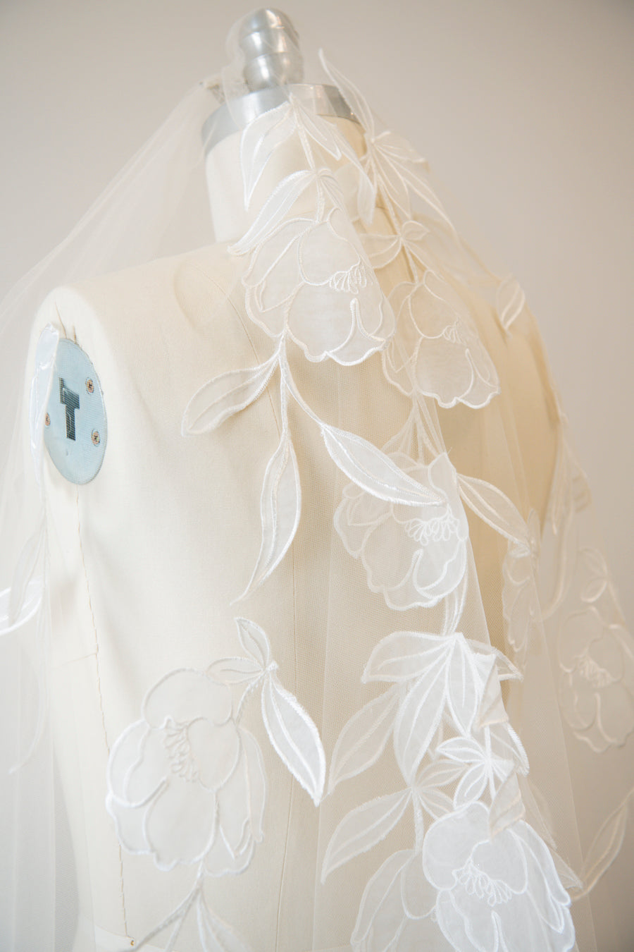 Handcrafted cathedral veil in warm ivory with floral embroidery from crown to fingertip, close up pictured on a mannequin