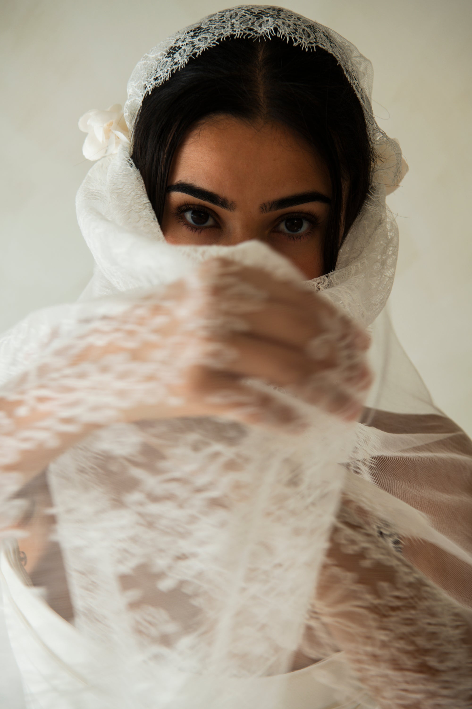 Bride holding Amélie Juliette cap veil across face, editorial bridal portrait