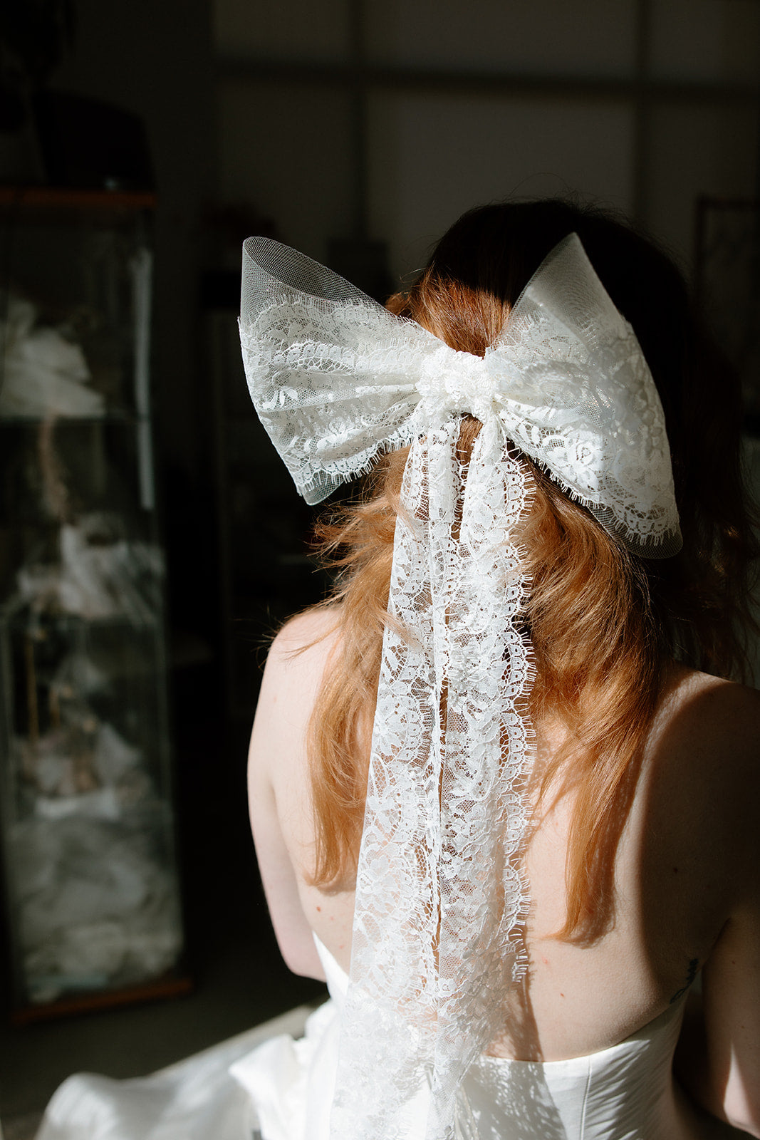 Bride wearing ivory Isla elbow length bow veil from back