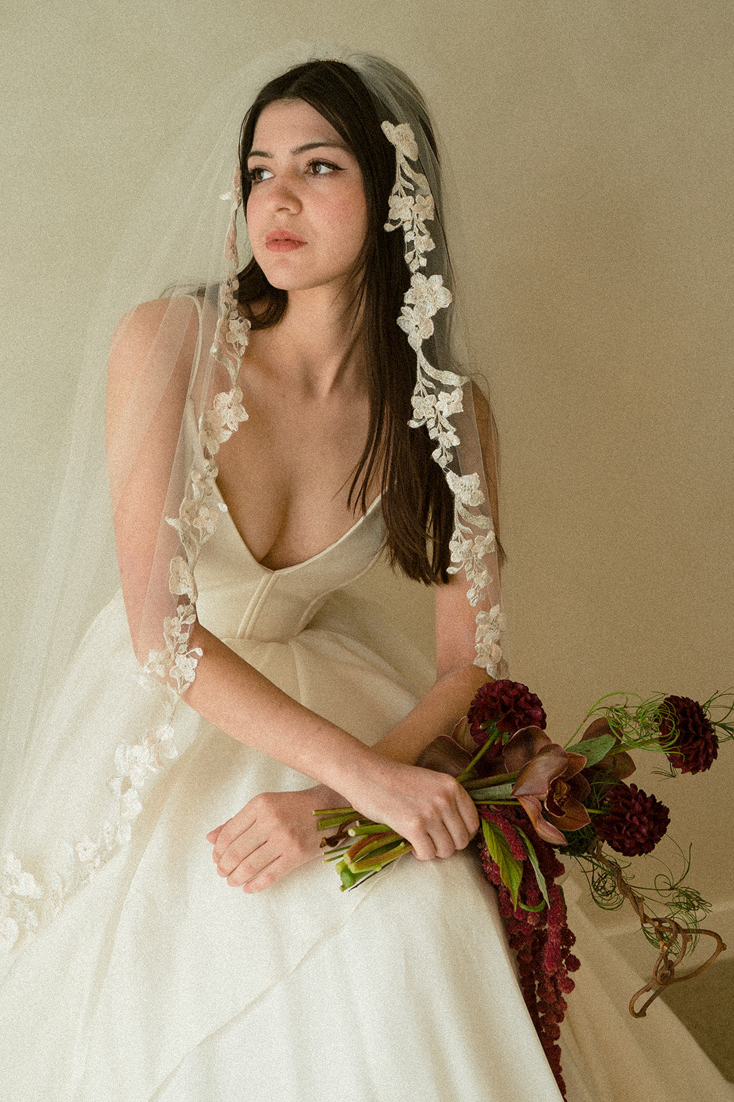 Bride wears Romantic fingertip veil with primrose embroidery while holding an anthurium bouquet