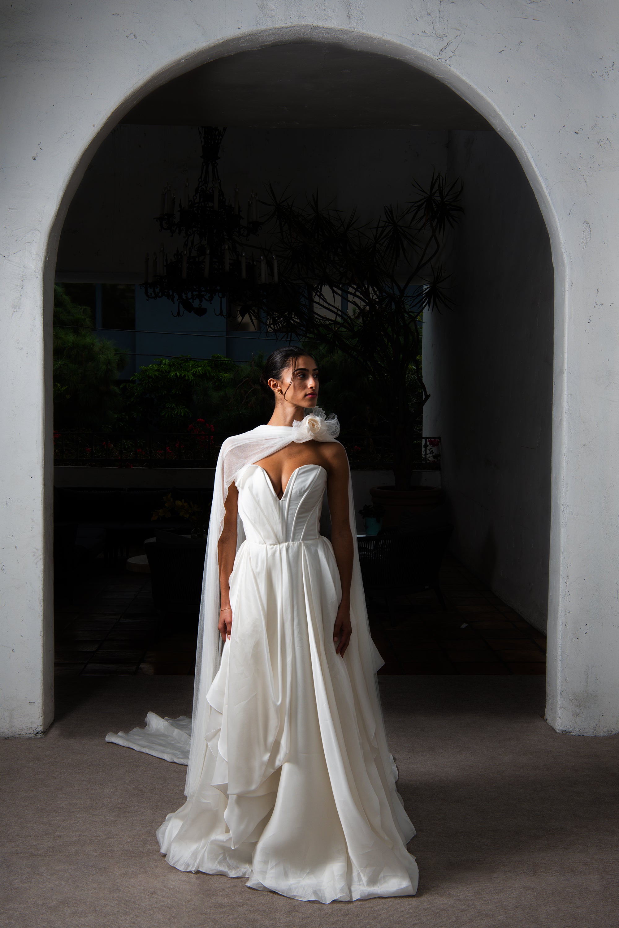 Bride wearing Renoncule brooch and silk tulle neck scarf under arch with wedding dress