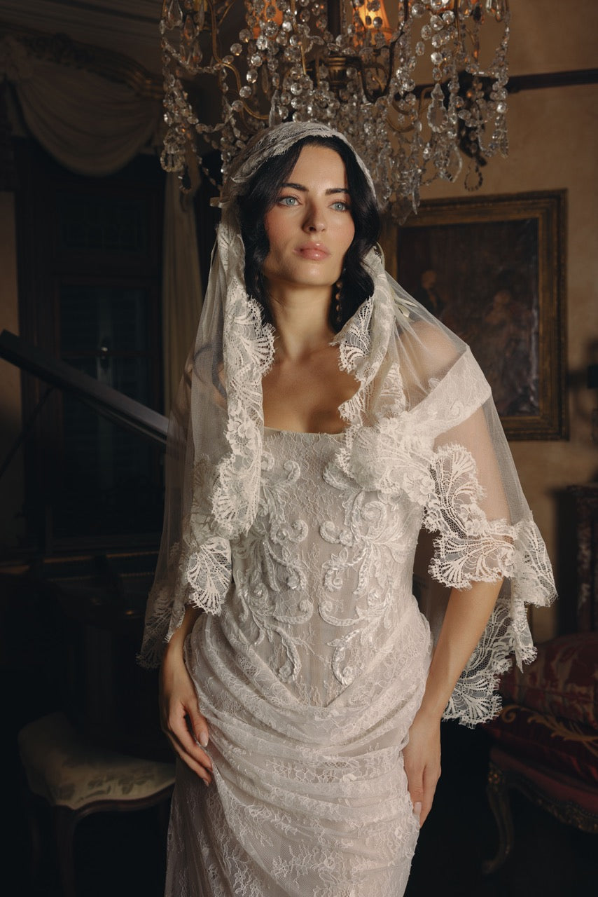 Emotive bride looking into the distance wearing a white dreamy wedding dress and a burgundy bouquet paired withAunyalune Vesper bridal veil 