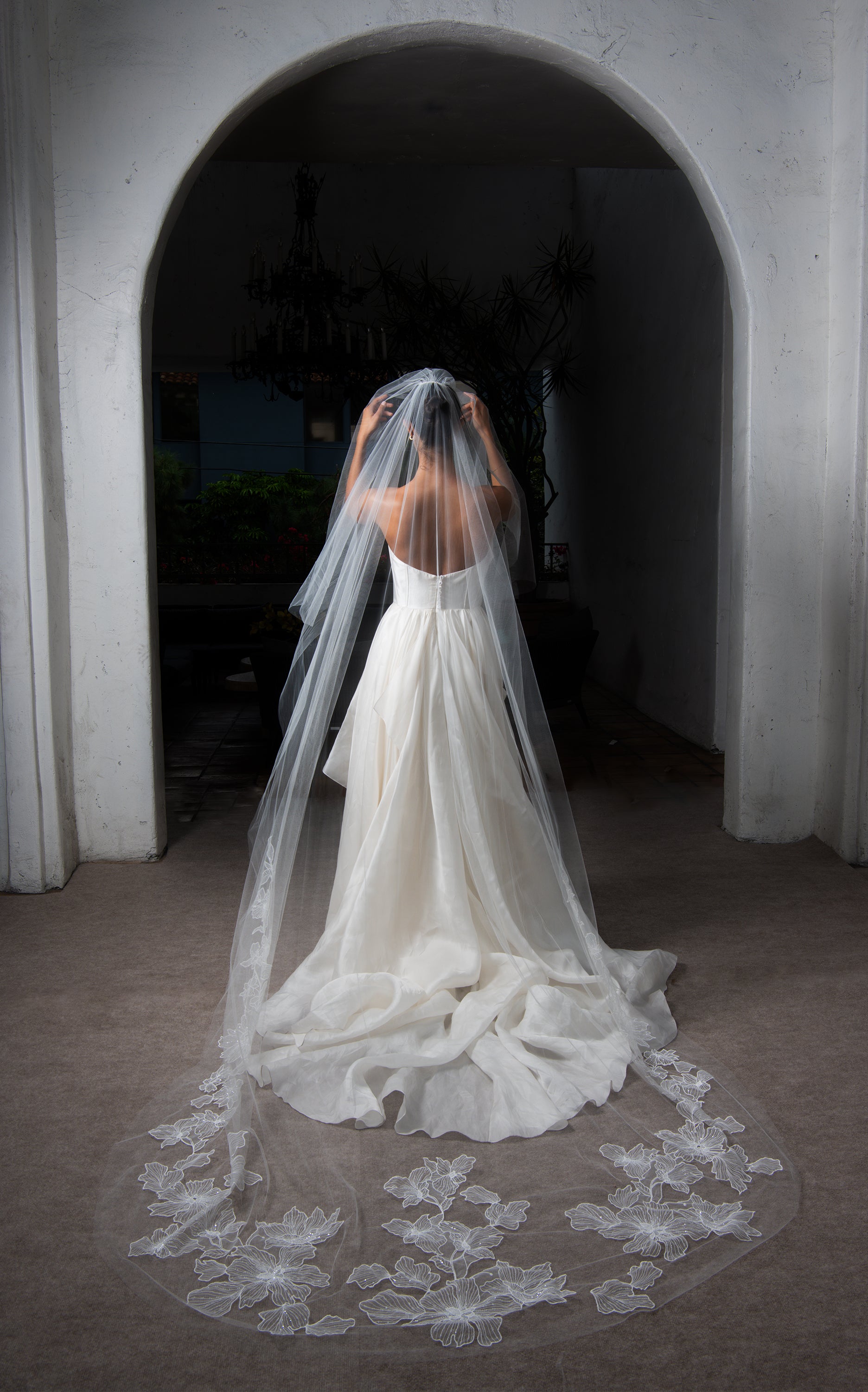 Chant d'Étoiles cathedral veil on bride, veil is spread under arch showing French floral embroidery and beading