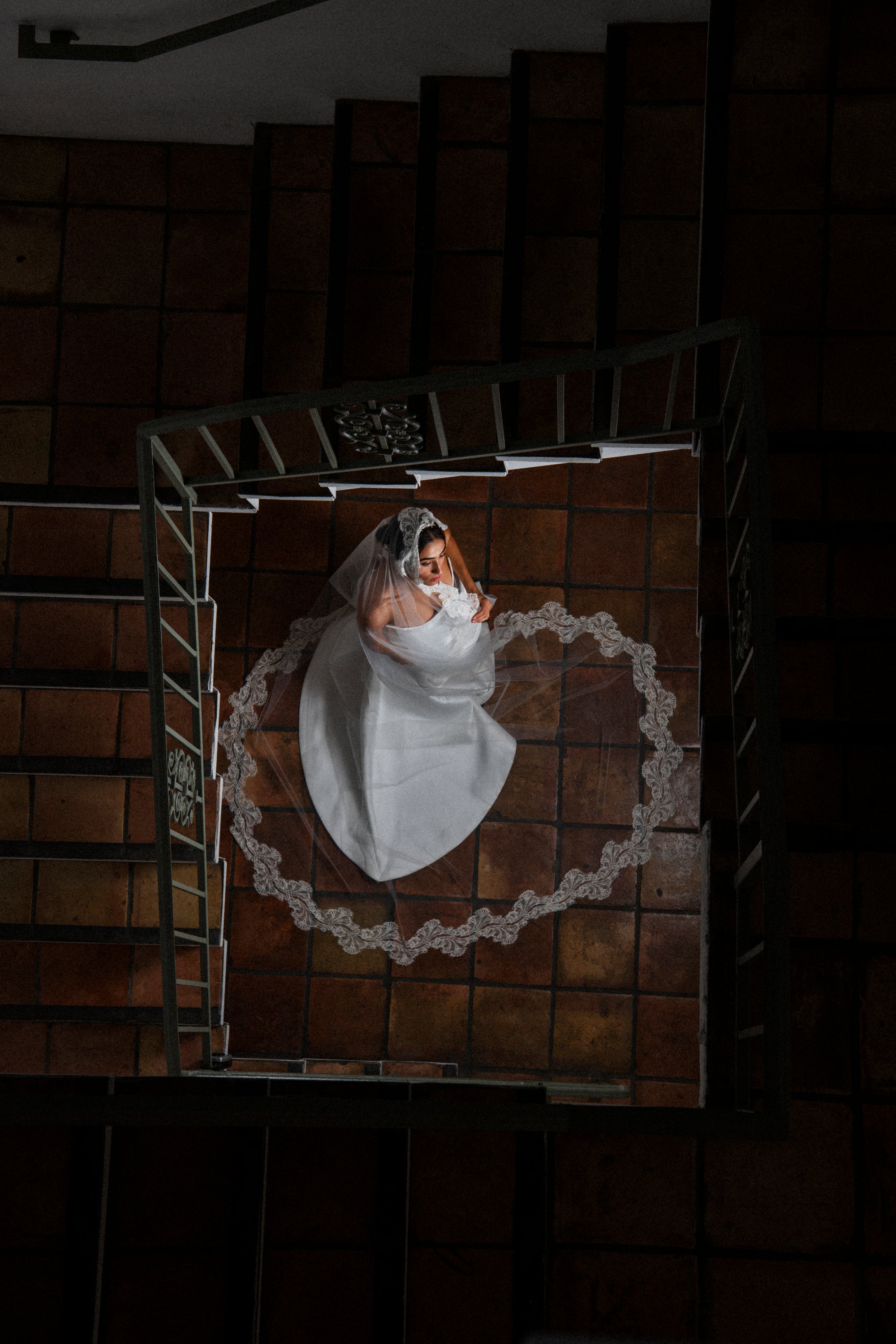 Top-down view of a bride in Clair de Lune cathedral mantilla veil by a staircase
